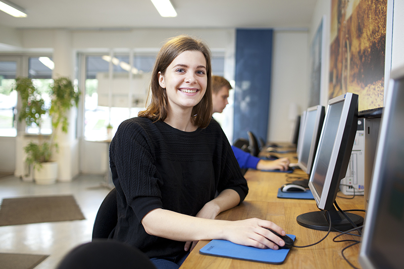 Kvinna sitter framför dataskärm.