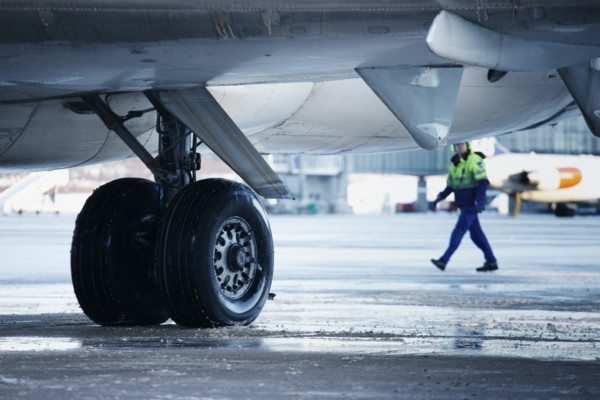 närbild flygplanhjul samt flygplan underifrån