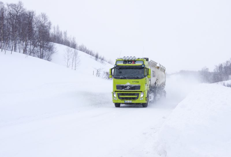 Lastbil kör på snöig vinterväg.